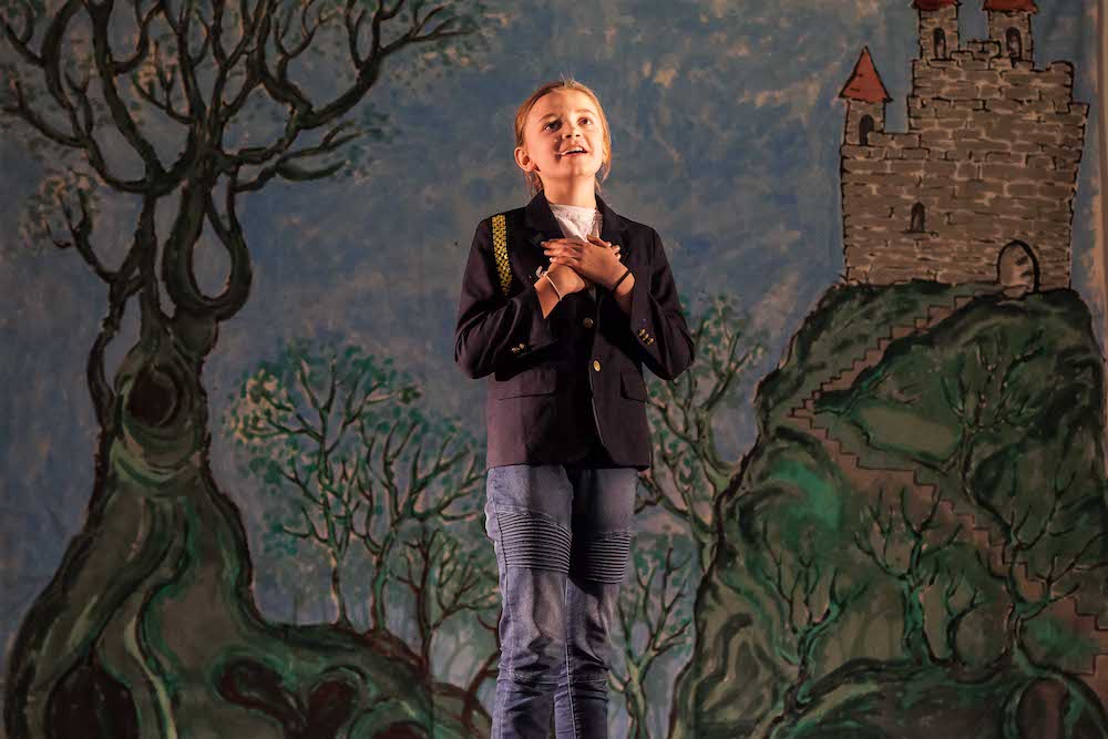 child on stage in front of a castle and tree